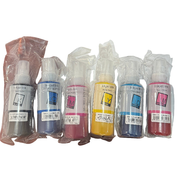 Set of ink bottles in various colors on a wooden desk with a keyboard in the background.